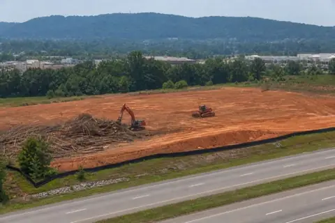 Commercial clearing beside an Alabama arterial with red-clay pad and silt fence