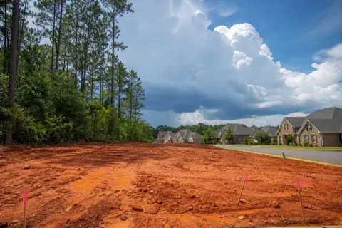 Wooded Alabama homesite partly cleared to red clay with survey stakes visible